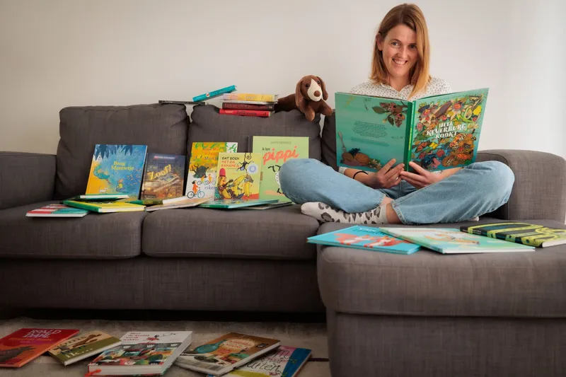 Laura op de bank, omringd door opengeslagen prentenboeken