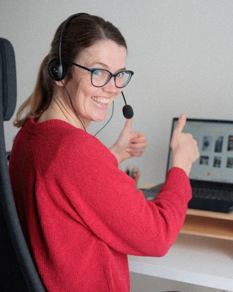 Laura steekt lachend haar duim op naast haar laptop