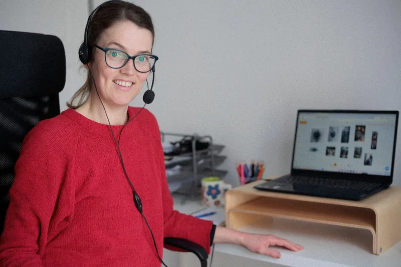 Laura met koptelefoon achter haar laptop, klaar voor een online les